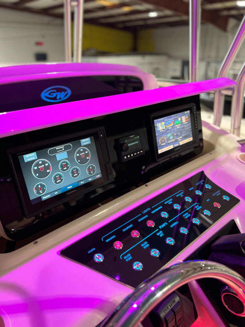 Grady‑White Bimini 306 dash close-up showing dual Garmin screens, stereo and illuminated labeled switch panel