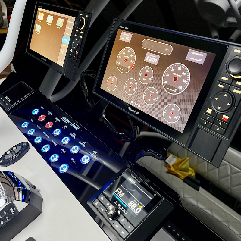 Angled view of Blue Wave Makaira dash panel with illuminated blue rocker switches and visible wiring beneath