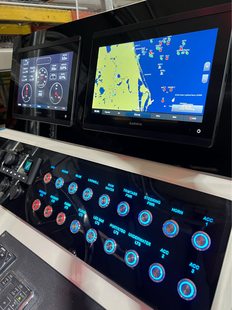 Angled close-up of Dusky 31 CC dash panel showing two Garmin displays and blue-backlit switches