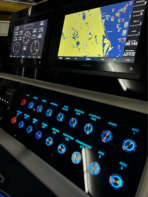 Dusky 31 CC dash panel at an angle showing rows of blue backlit labeled switches and Garmin screens.