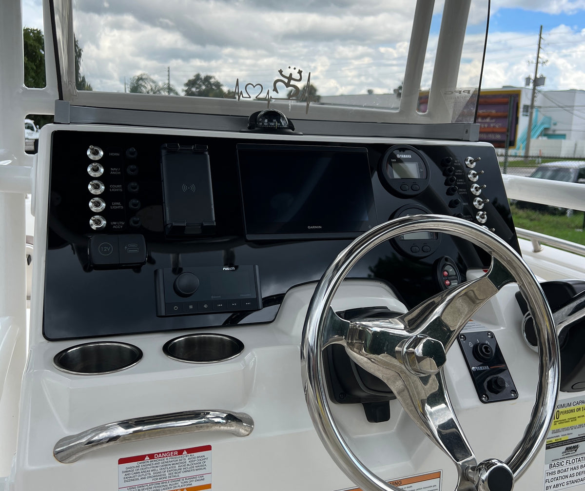 Front helm view of Robalo R222 showing Garmin display, compass, labeled switches and steering wheel.