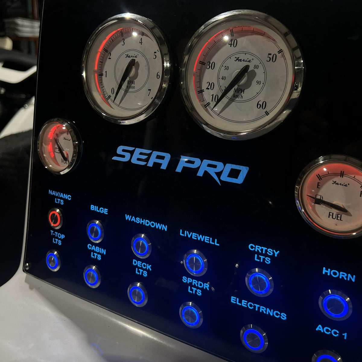 SEAPRO 220 CC dash panel angled close-up showing chrome gauges with red accents and blue backlit switches