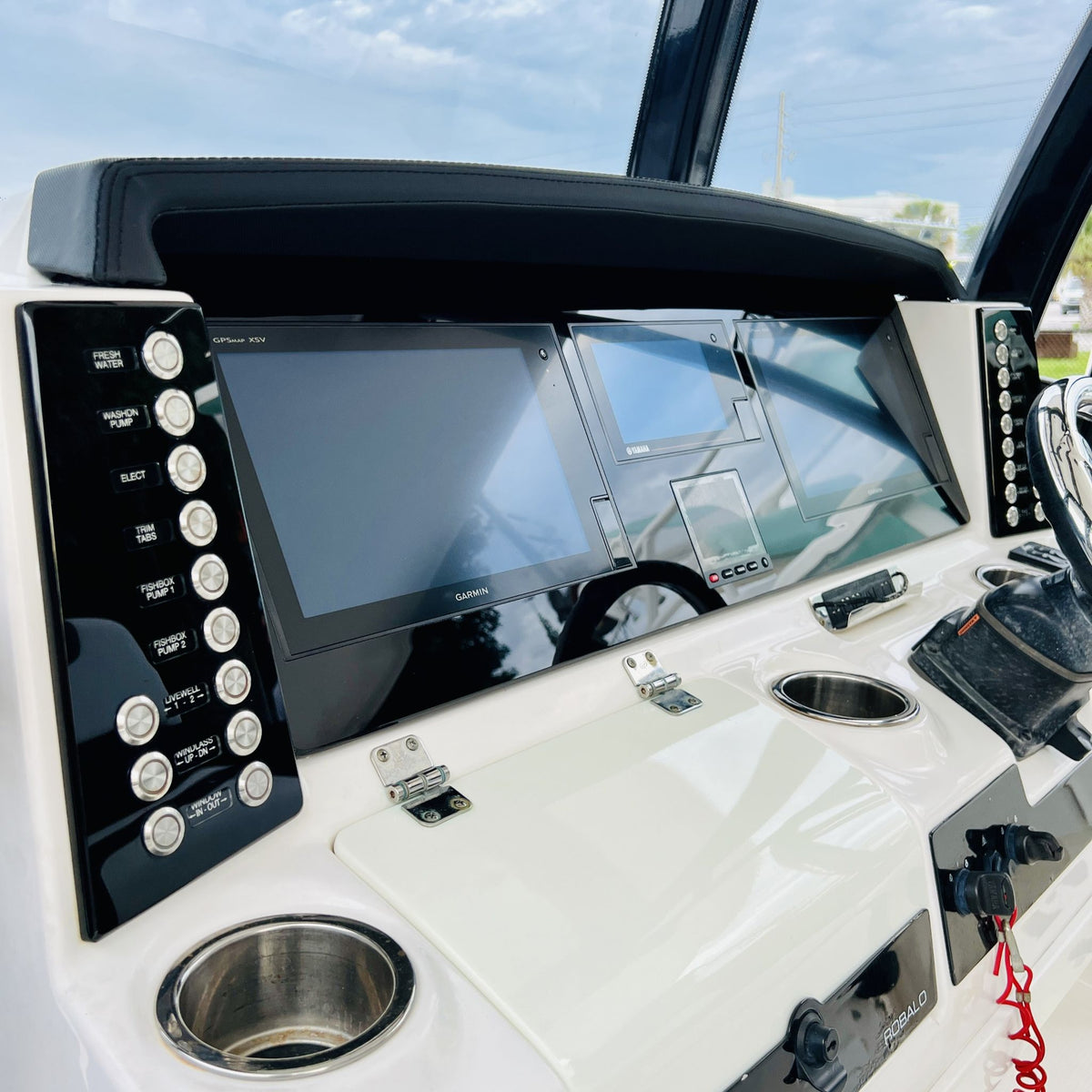 Robalo R302 dash close-up showing dual Garmin screens, left/right switch panels and cup holder.