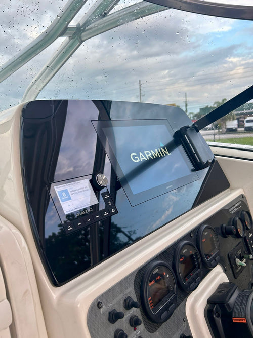 A Garmin GPS and navigation screen mounted on the helm console of a boat, with other controls and a windshield visible in the background.
